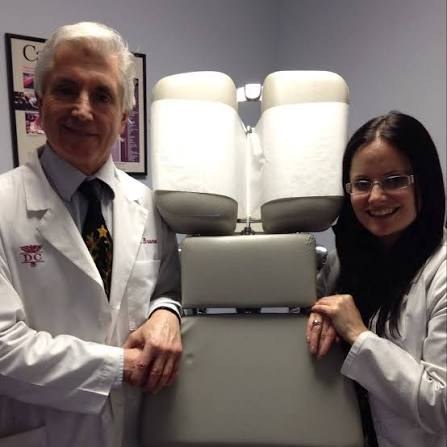 Dr. David Bruno and Dr. Erika Bruno standing beside a chiropractic treatment table in their office