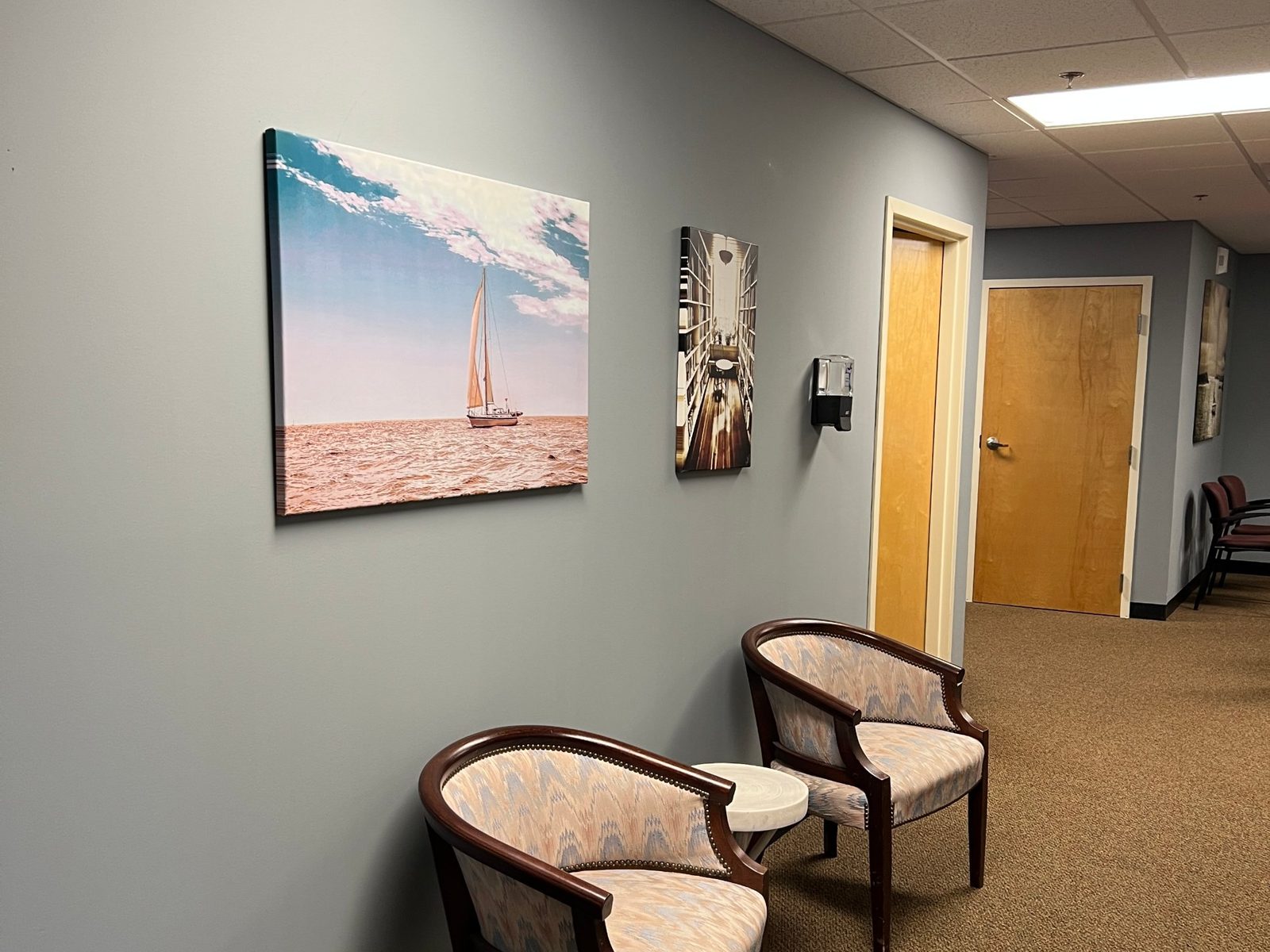 Hallway seating with a sailboat canvas on a soft blue-grey wall