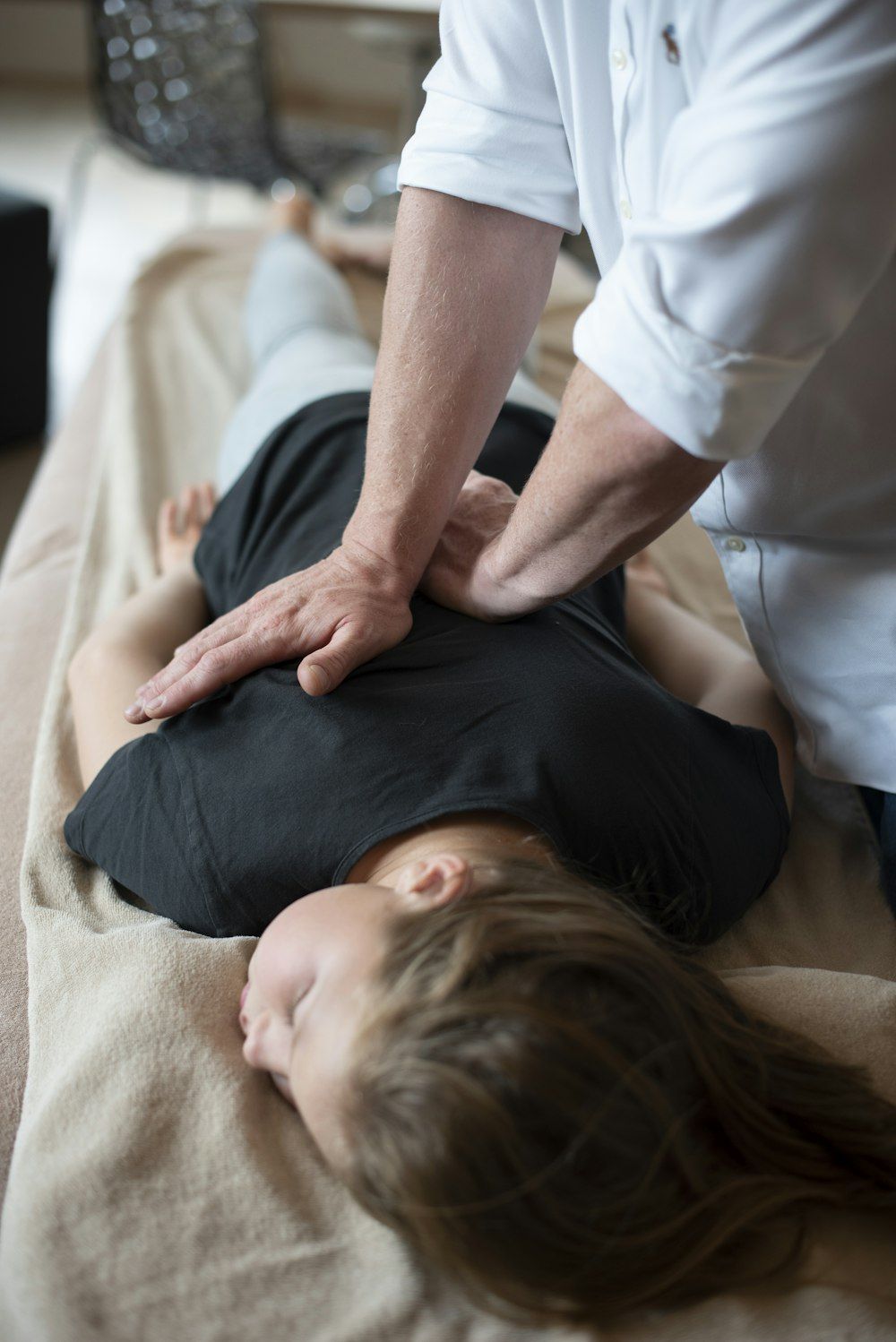 Chiropractor's hands placed on a patient's upper back